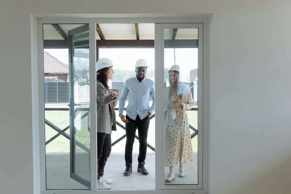 Contractor and homeowners wearing hard hats discussing the project during an onsite walkthrough.