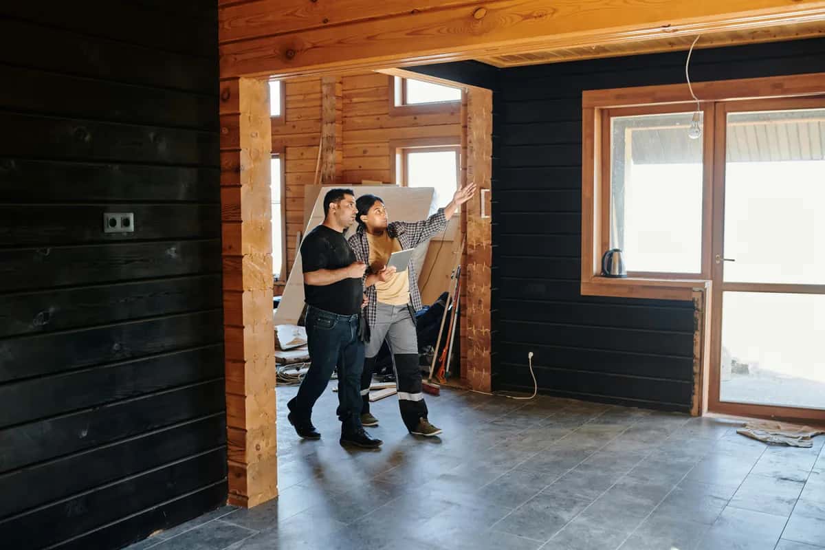 Two workers inside a home under renovation, reviewing work in a partially constructed room.